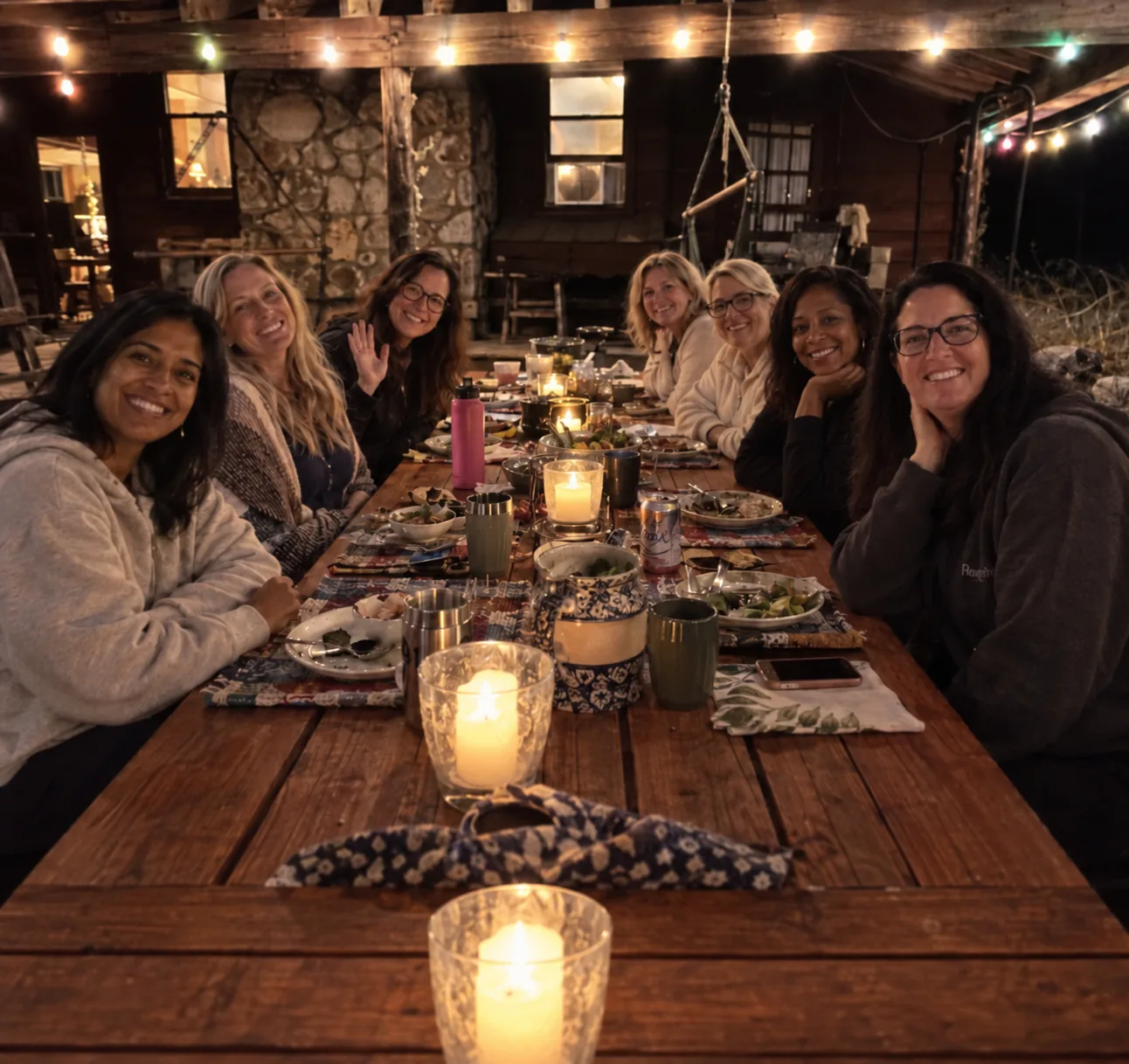 Seven women sharing dinner at a candlelit table during a retreat